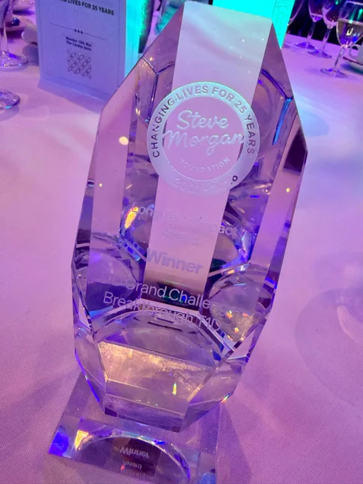 Crystal award on a table with engraved text for the Steve Morgan Foundation, marking 25 years.