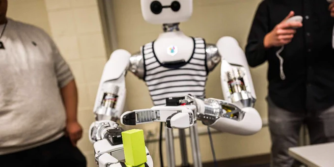 Reachy the Robot stacks green blocks in a Michigan Tech lab. 