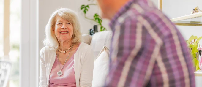 Elderly woman laughing with partner in home.