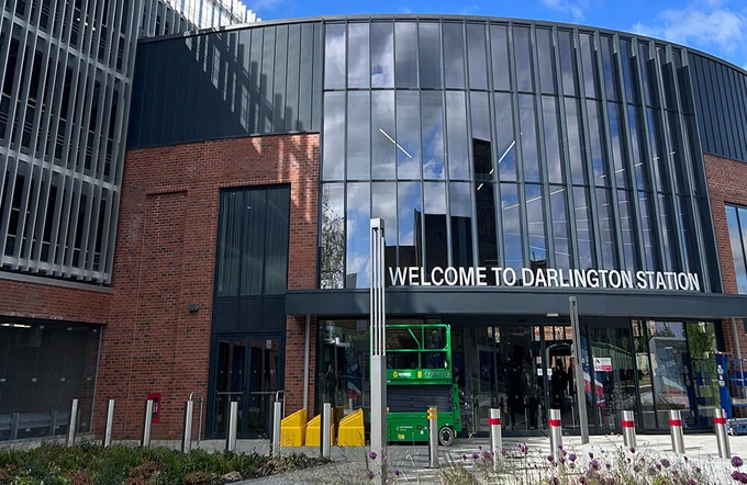 Modern station entrance with a Welcome to Darlington Station sign.