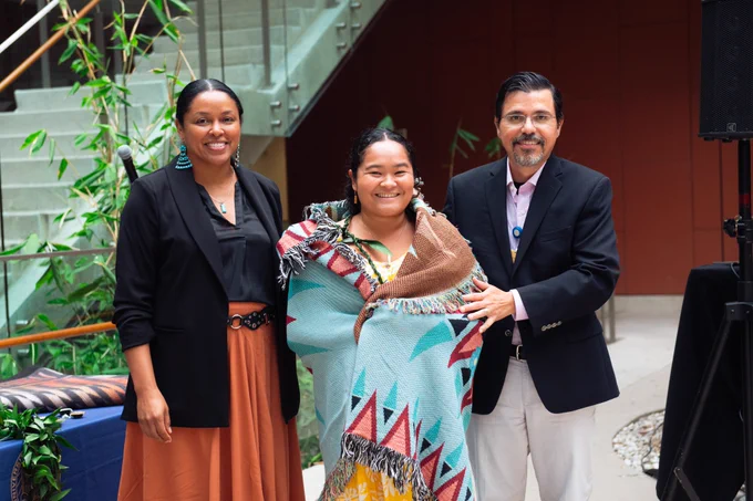 A PRIME-TIDE student is given their blanket by two faculty in the ceremony.