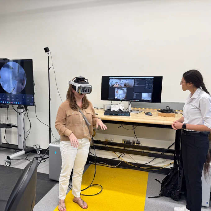 Shelby Page uses VR headset to experience simulation of vision impairment in GT lab alongside graduate research assistant, Parisa.