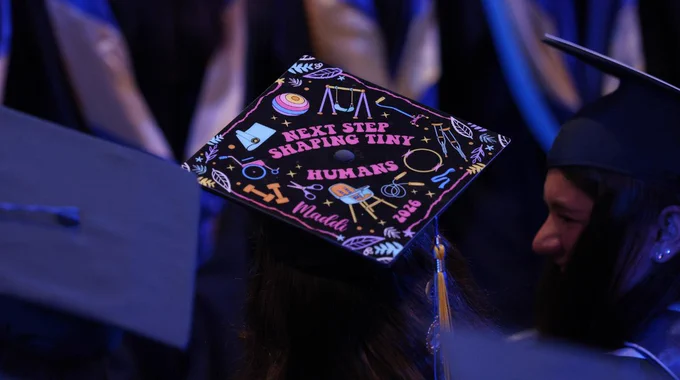 A decorated graduate cap that says, "Next step: shaping tiny humans."