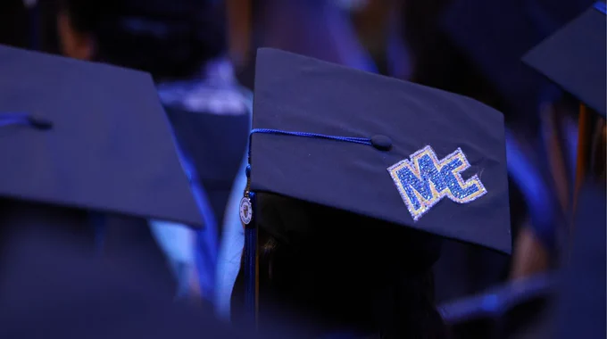 A decorated graduate cap with the MC logo. 