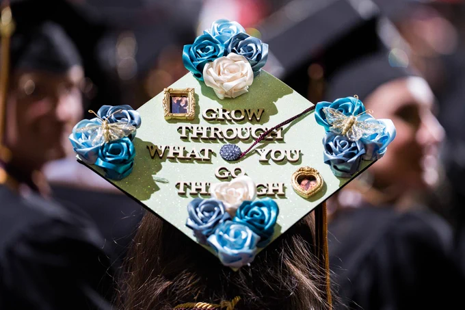 Back of a graduation cap decorated with blue flowers and text reading "grow through what you go through"