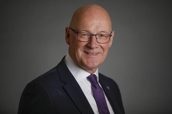 A portrait of John Swinney MSP, he is smiling. 
