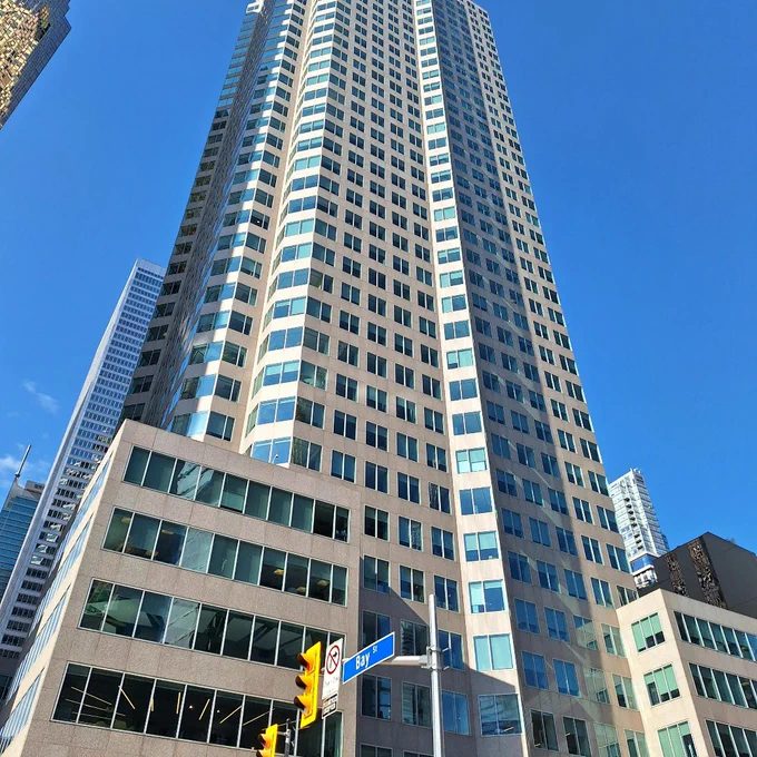 Tall modern skyscraper with reflective windows under a clear blue sky in an urban setting.