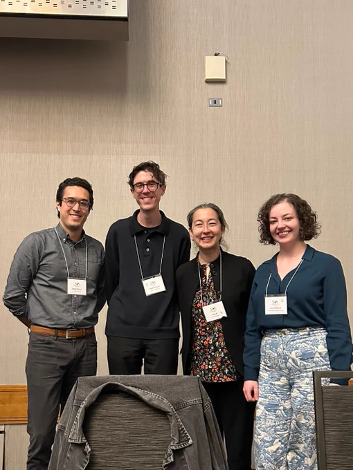 Four panelists stand behind a table. End ID.