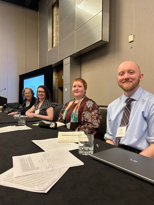 Four panelists sit behind a table. End ID.