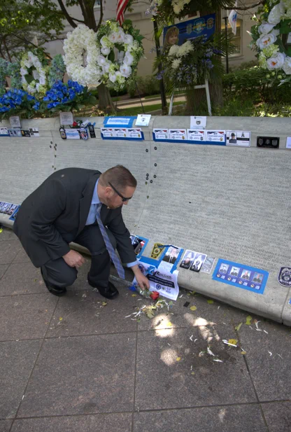 Director L. Scott Moreland lays a single red rose in memory of a fallen CID agent next to it's memorial wall inscription. 
