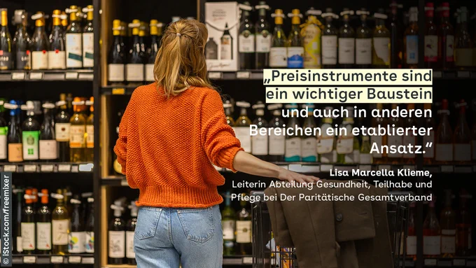 Eine Frau steht mit ihrem Einkaufswagen for einem prall gefüllten Spirituosen-Regal.
