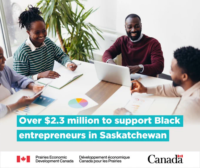 A group of Black entrepreneurs are smiling and sitting around a table with a laptop and various pieces of paper showing charts and graphs. With text: “Over $2.3 million to support Black entrepreneurs in Saskatchewan”.
