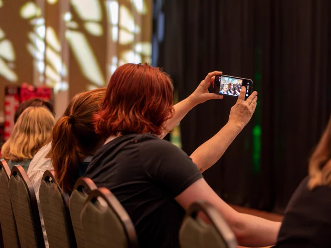 Two audience members take a selfie together while seated at a Music Industry Summit panel.