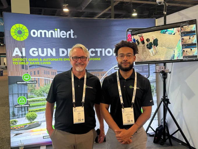 Omnilert team members Dan (left) and Wyatt (right) stand in front of the Omnilert booth backdrop at ICSC LV 2026.