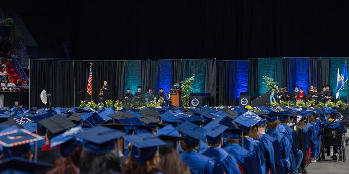 A large graduation ceremony takes place in an auditorium. 