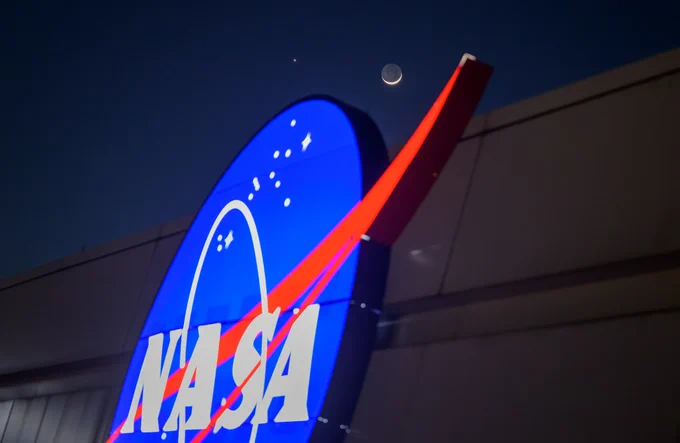 The crescent moon and Venus, photographed in the sky just above the glowing NASA insignia on the Mary W. Jackson NASA Headquarters Building in Washington, D.C. Credit: NASA/Bill Ingalls