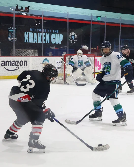 Photo of an adult hockey game on an indoor ice rink. A player is shooting a puck at the goalie.