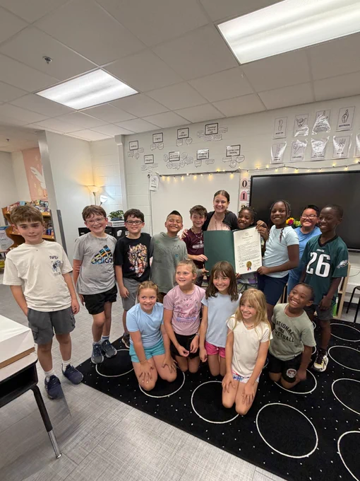 Mrs. Foster holds proclamation and is surrounded by her students.