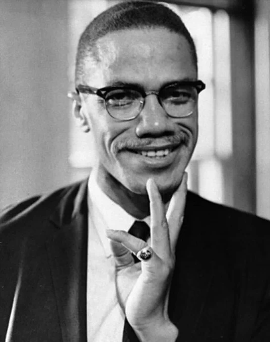 black and white photo of malcolm x smiling