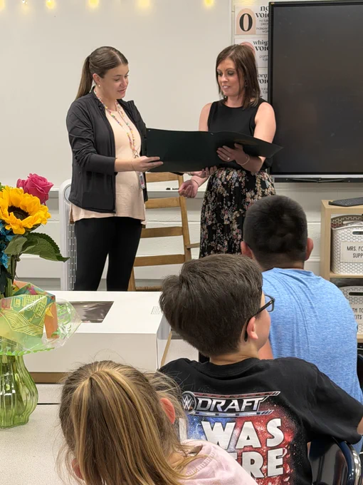 Mrs. Foster is presented with a proclamation by Lexy Beckwith in front of the classroom.