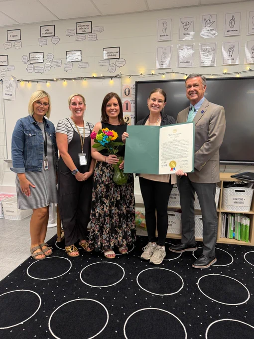 Mrs. Foster holds the proclamation and stands alongside Lexy Beckwith, her school admins and Director of Schools in front of the classroom.