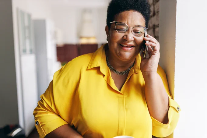 An older woman smiles as she talks on the phone.