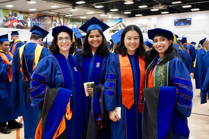 Four PhD graduates smile for a group photo.