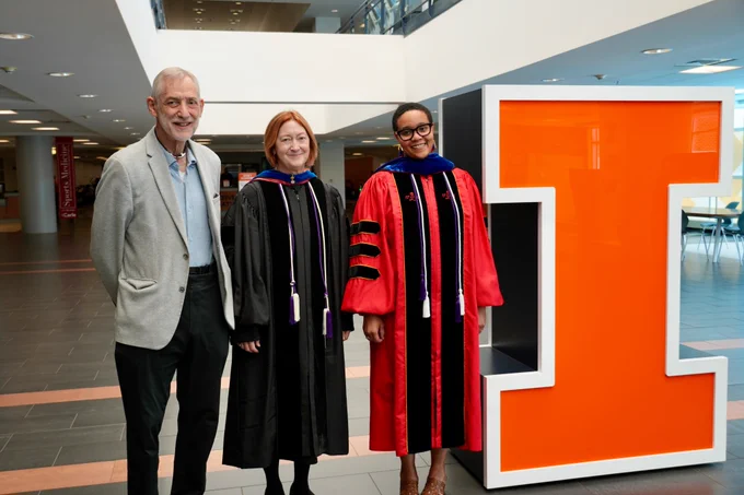 Interim Dean Emily Knox smiles alongside Michèle Cloonan (MS '84, PhD '88) and Sid Berger (MS '87) next to the block I at the ARC. 