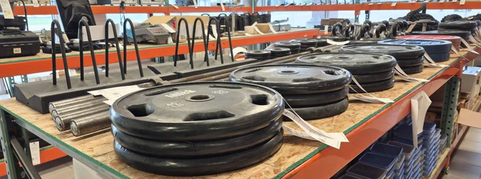 Various weightlifting and exercise equipment laid out on a table at Surplus.