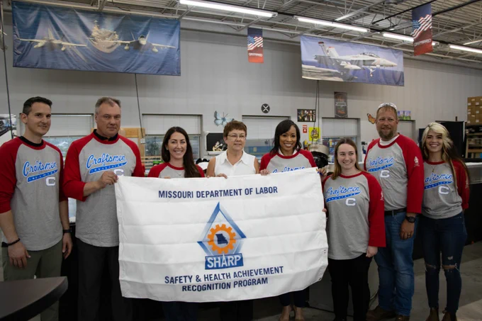 Craftsman Industries safety commission holding newly awarded SHARP flag for their accomplishment in safety.