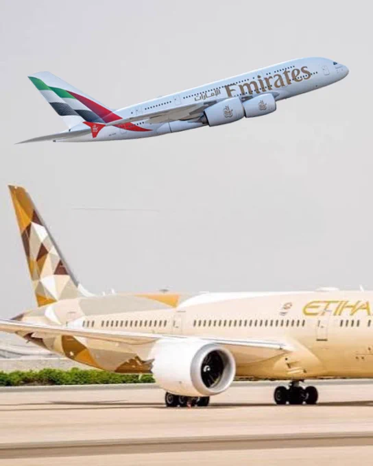 Picture of an Emirates plane taking off over the top of an Etihad plane sitting on the airfield