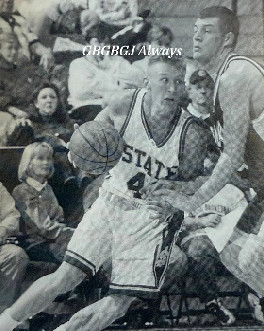 A basketball player in a "State" jersey with the number 4 is dribbling the ball, closely guarded by a player from "Kansas." The scene takes place on a court with spectators visible in the background. The words "GBGBGJ Always" are superimposed at the top of the image.