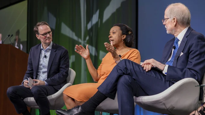 Three people seated on a stage having a discussion.