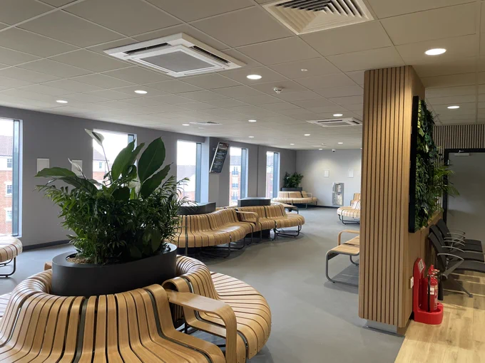 Indoor waiting room with different seating options, fake greenery and display boards