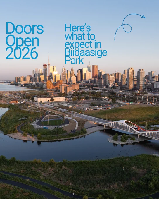 Aerial view of a city skyline featuring tall buildings with a prominent tower. In the foreground, a river with a modern bridge and green parkland is visible. The text reads: "Doors Open 2026. Here’s what to expect in Bildaasige Park."