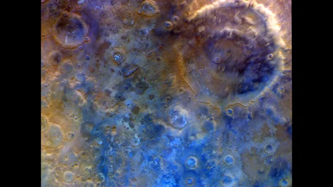 A colorful landscape of craters, including one larger crater with concentric rings