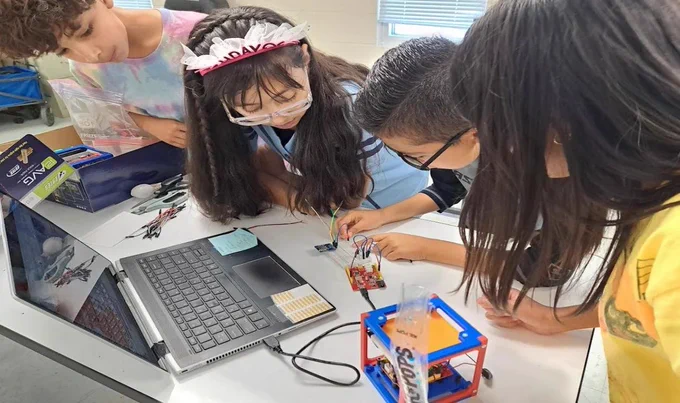 Young students work together to assemble a CubeSat in class.