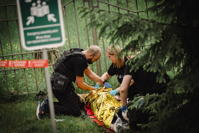Participants of a tactical emergency casualty care training provide first aid to a simulated casualty outdoors