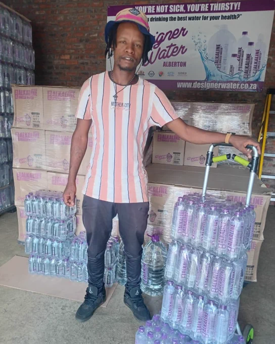 A message welcoming Simphiwe to the team in Alberton. We see Simphiwe smiling, standing next to stacks of Designer Water pH10, in a warehouse in Alberton, South Africa