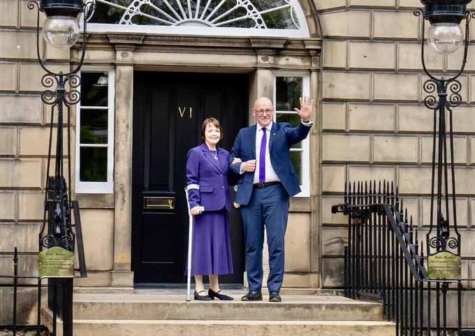 John Swinney and his wife Elizabeth waving to people on the steps of Bute House, in front of the black door