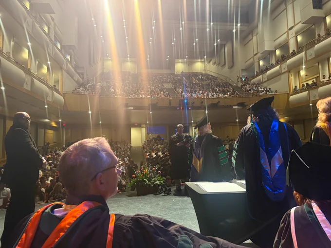  A photo taken from on stage at a graduation ceremony, looking out over the crowd assembled in a large auditorium.