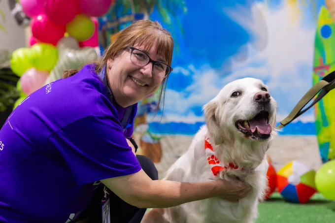 Nurse smiling while petting a therapy dog