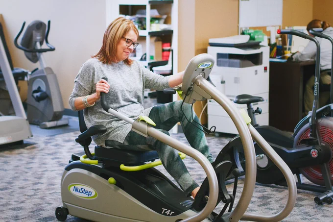 Woman using a NuStep T4r recumbent cross trainer in at Gina V physical therapy in Papillion Nebraska