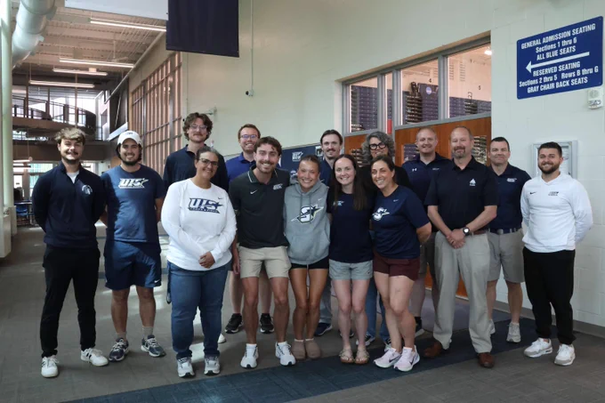 A group photo of UIS runner Maddie Miller-Ross, coaches, staff, and campus community members