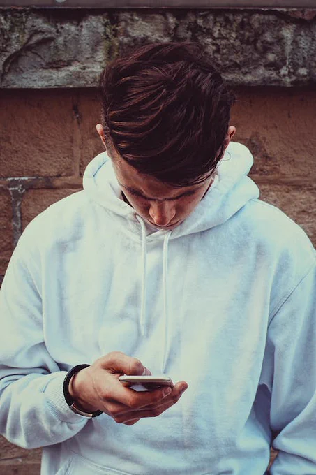Image of a teenage boy looking down at his phone