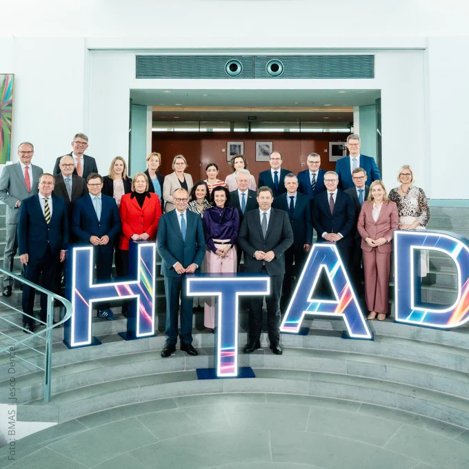 Das Bundeskabinett der aktuellen Bundesregierung steht auf einer Treppe und posiert für eine Foto. Auf der Treppe sind folgende große LED-Buchstaben verteilt: HTAD.