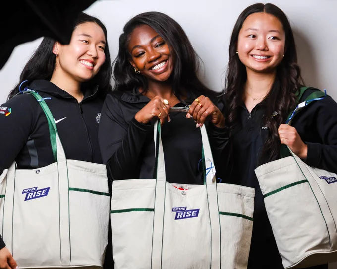 Photo of three women's student-athlete showing off the new OUA On the Rise tote bag
