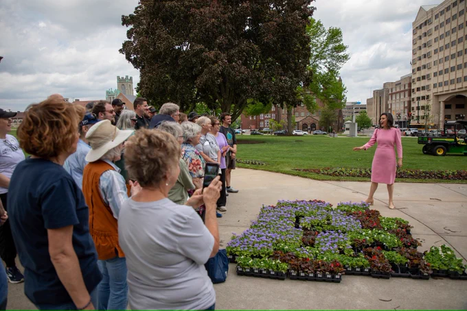 Gov. Whitmer stands in front of Michigan Capitol flowers alongside volunteers.