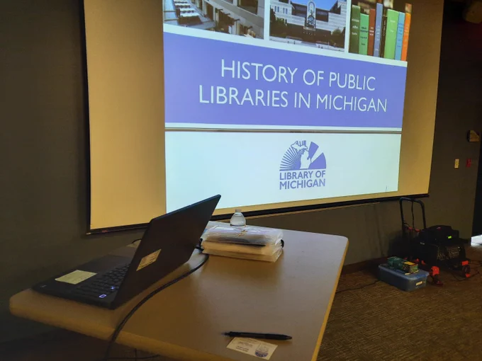 Computer and screen showing the "History of Public Libraries in Michigan" slide.