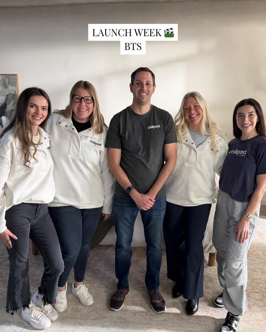 A group of five team members stand together, smiling for a photo during launch week. The mood is upbeat and collaborative.